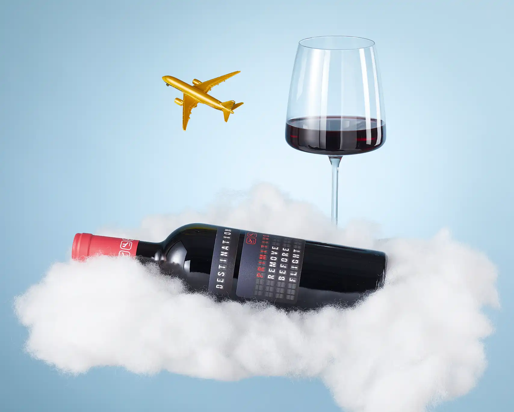 Eine Flasche Wein auf Wolken liegend mit Flugzeug und einem Glas Rotwein